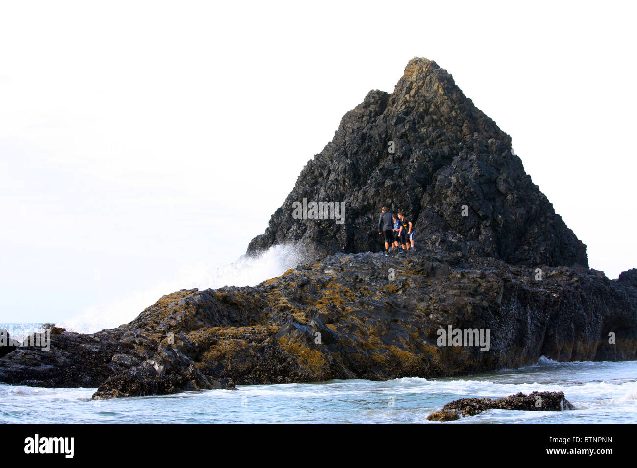 40,459.07501 tre giovani ragazzi sfidano il pregiudizio e la morte come loro oggetto di scherno la collera del surf e grandi onde dell'oceano mentre intrappolati su un isola di roccia. Foto Stock