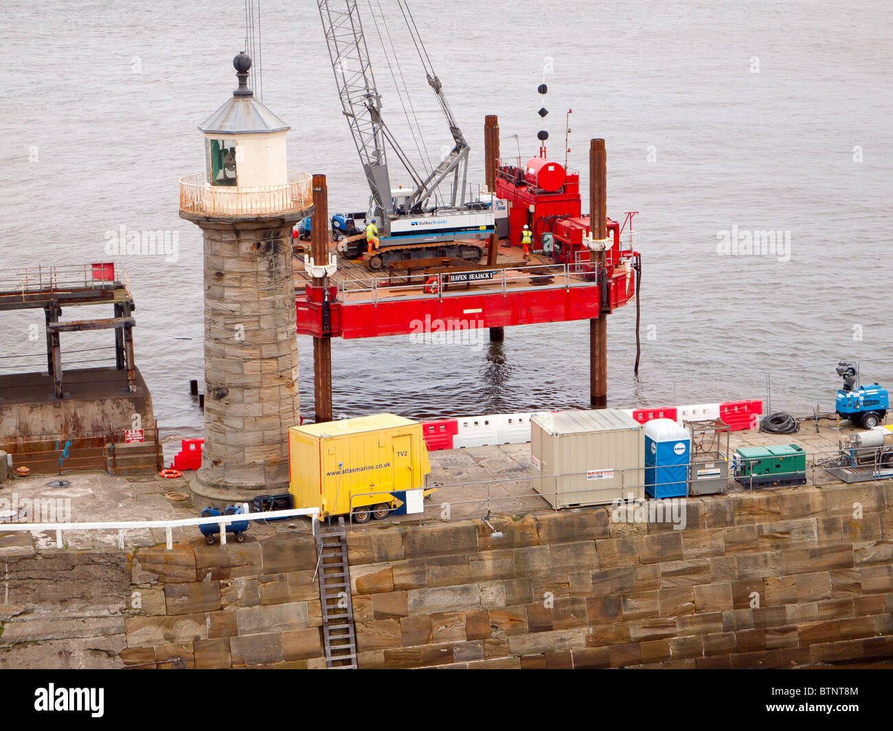 Una ingegneria civile jack-up rig Haven Seajack effettuazione di riparazioni per il mare la parete est del molo Whitby Foto Stock