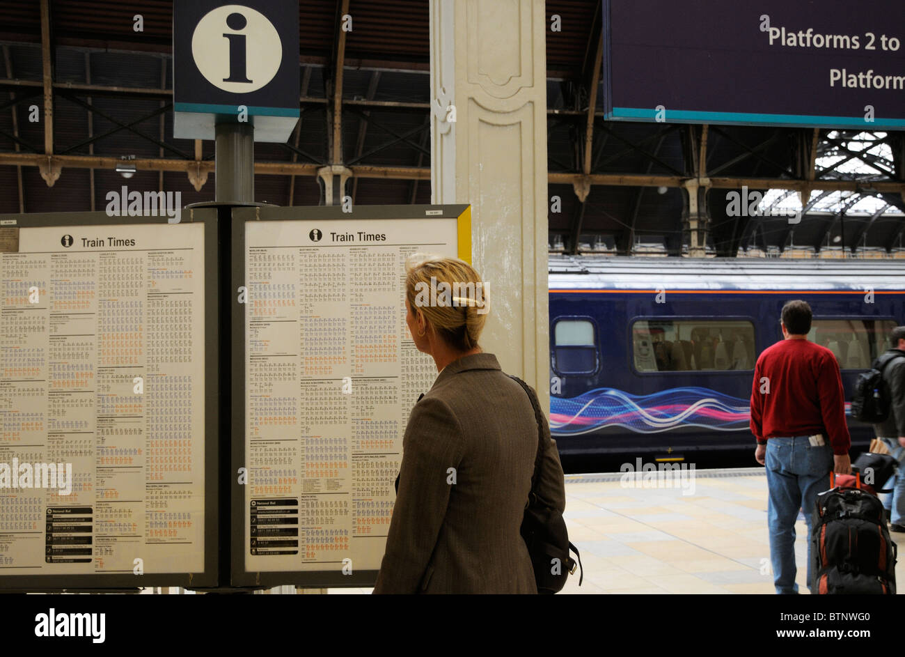 Imprenditrice in piedi sulla piattaforma di visualizzazione gli orari dei treni e informazioni scheda Stazione di Paddington a west London REGNO UNITO Foto Stock