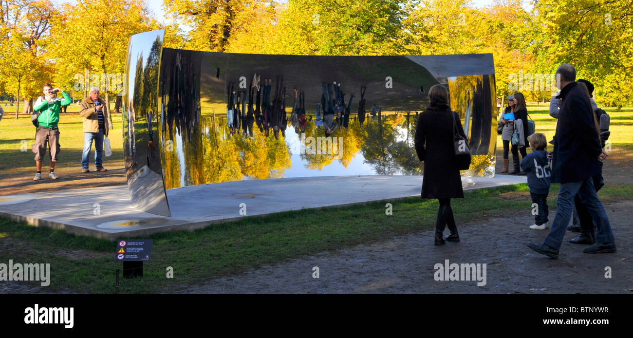 I turisti che visitano i Kensington Gardens hanno visto immagini riflesse di se stessi in uno degli specchi Anish Kapoor Sky Mirrors C Curve London Inghilterra UK Foto Stock