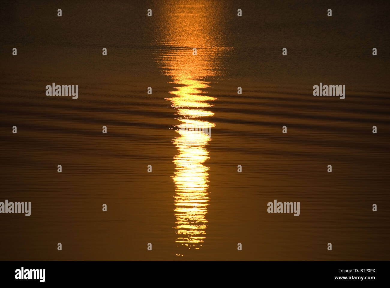 La riflessione del sole sulle increspature dell'acqua al tramonto Foto Stock