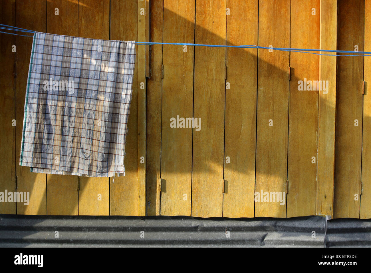 Asciugamano appeso su una linea di lavaggio con giallo sullo sfondo di legno Foto Stock