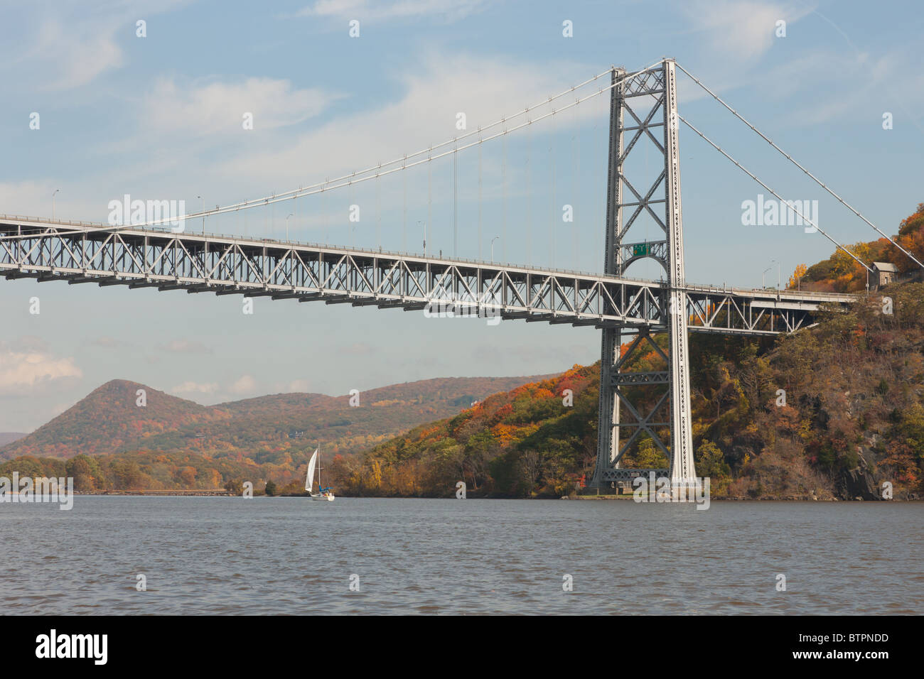 Una barca a vela sul fiume Hudson passa sotto il Bear Mountain Bridge in autunno Foto Stock