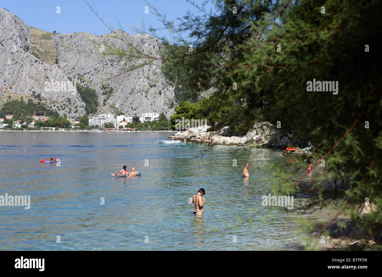 Persone giocare sulla spiaggia vicino alla città vecchia di Omis Croazia Foto Stock