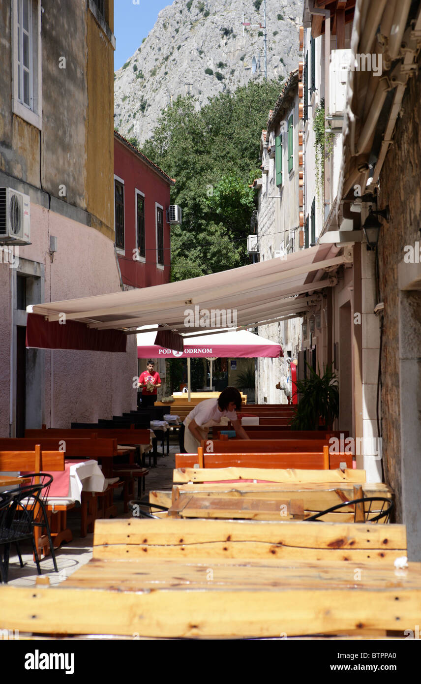 Una cameriera prepara la tavola in una stradina nel centro storico della città di Omis Croazia Foto Stock