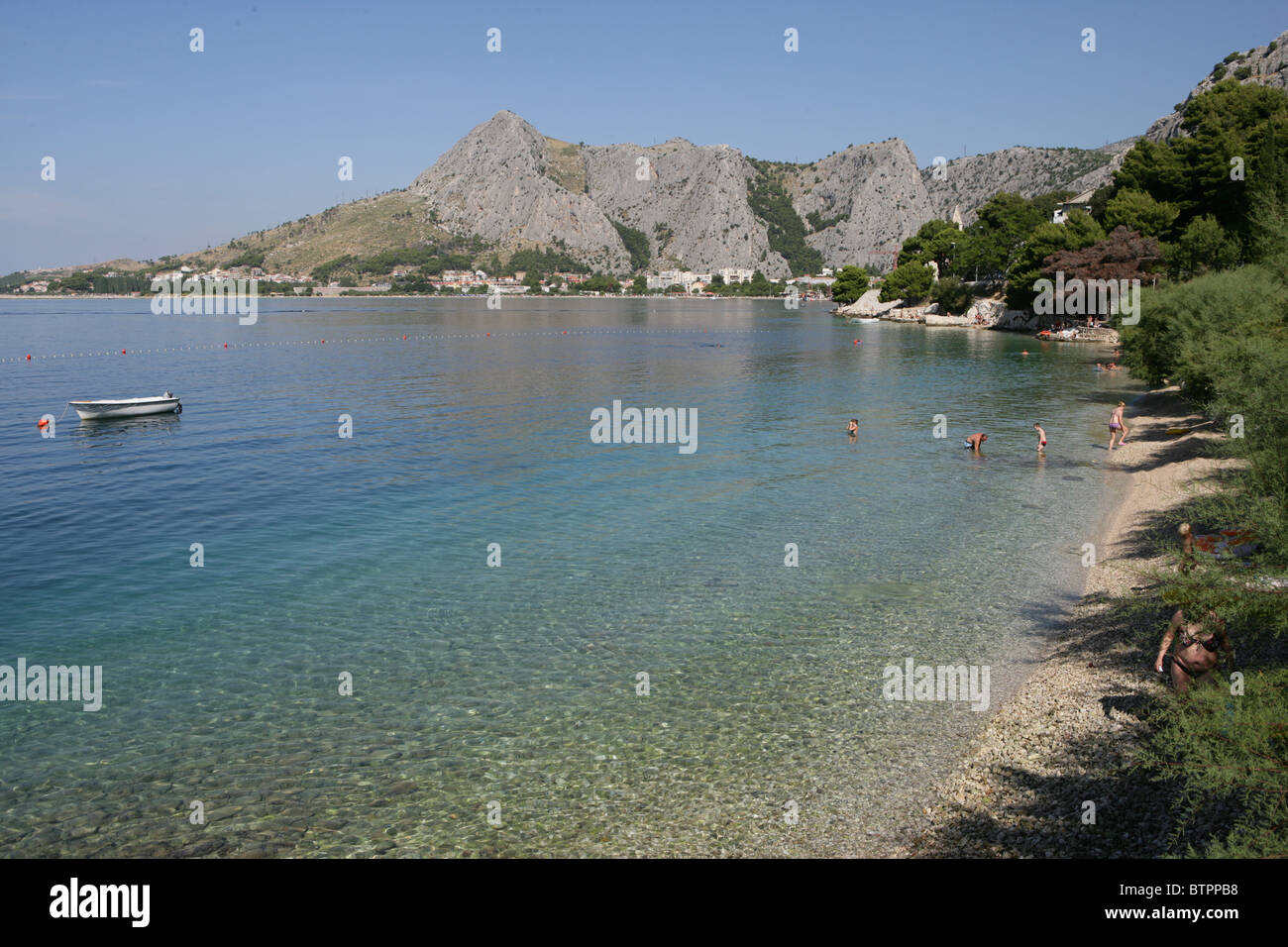 Persone giocare sulla spiaggia nelle limpide acque vicino alla vecchia città di Omis, Croazia Foto Stock
