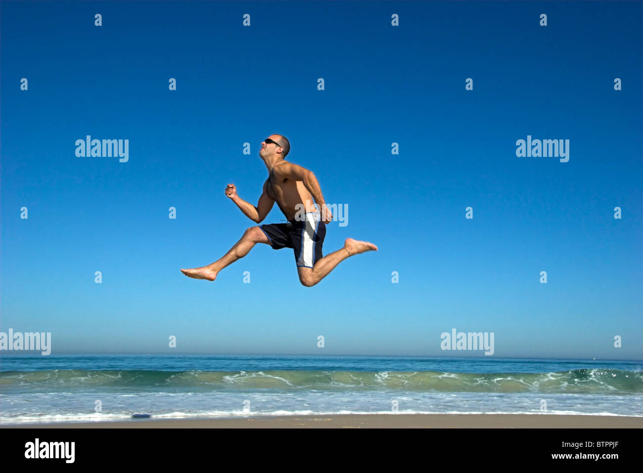 Uomo che corre e salta sulla spiaggia Foto Stock