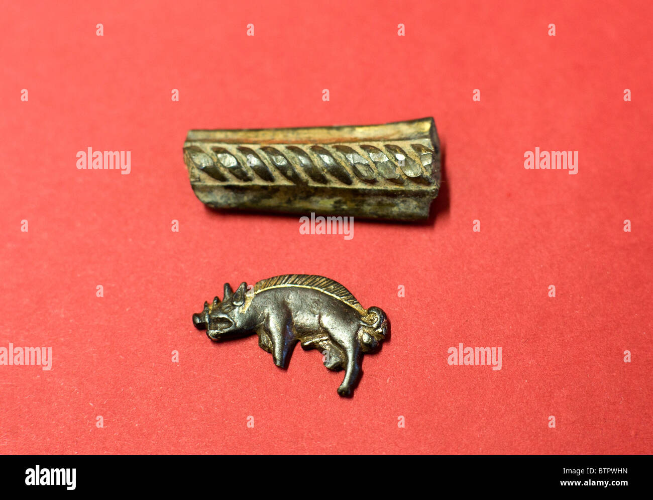 Un argento dorato del cinghiale badge e parte dell'elsa da una spada trovata nel nuovo sito della battaglia di Bosworth. Foto Stock