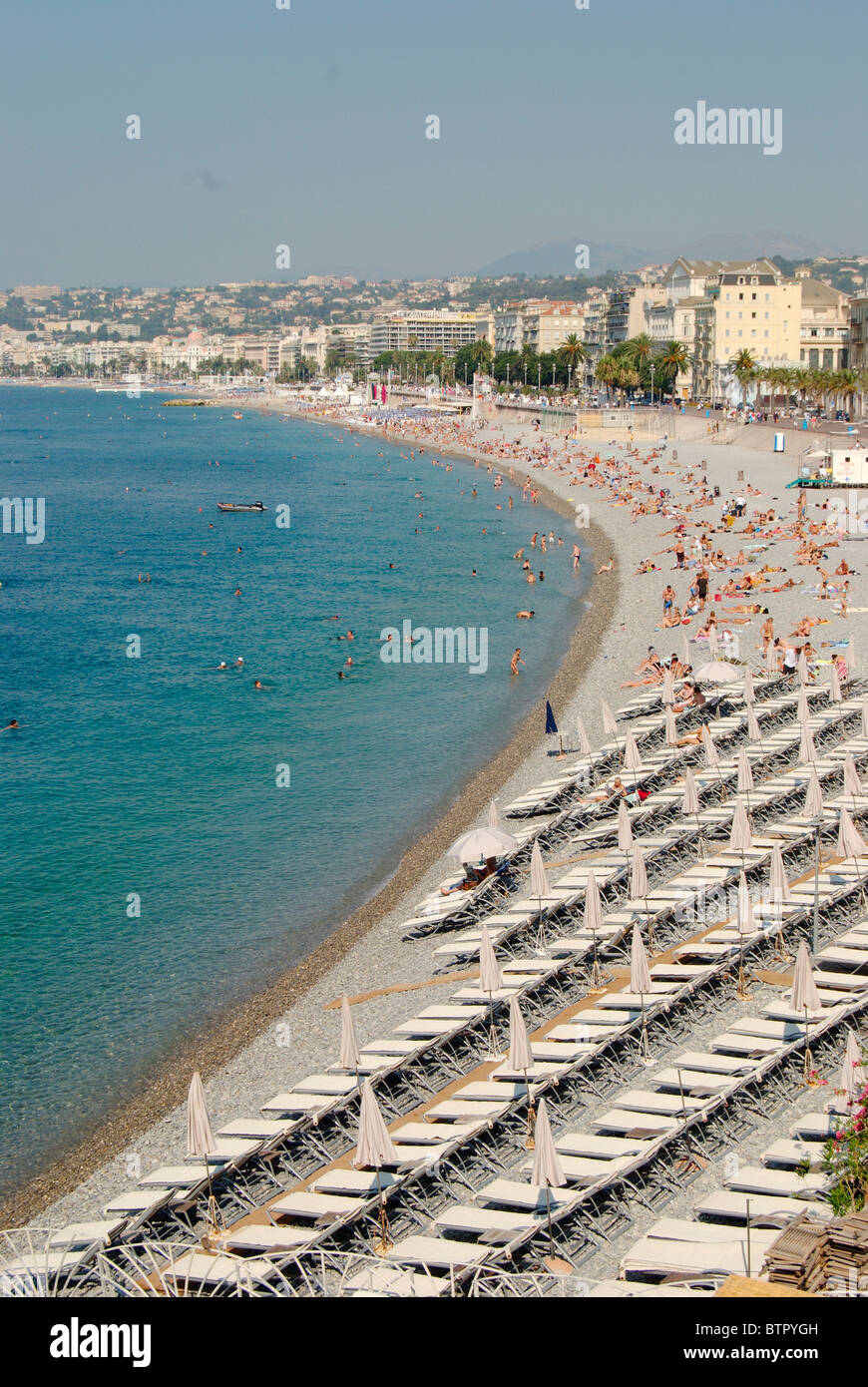 Francia, Nizza Promenade des Anglais, gran numero di sedie a sdraio e persone presso la spiaggia e la città in background Foto Stock