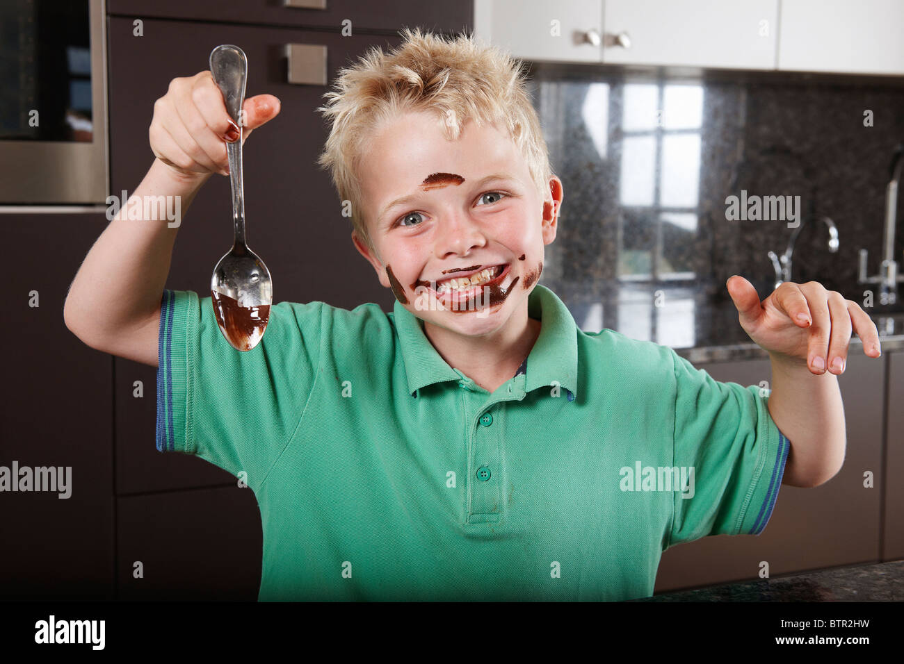 Ragazzo in cucina con cake mix sul suo volto Foto Stock