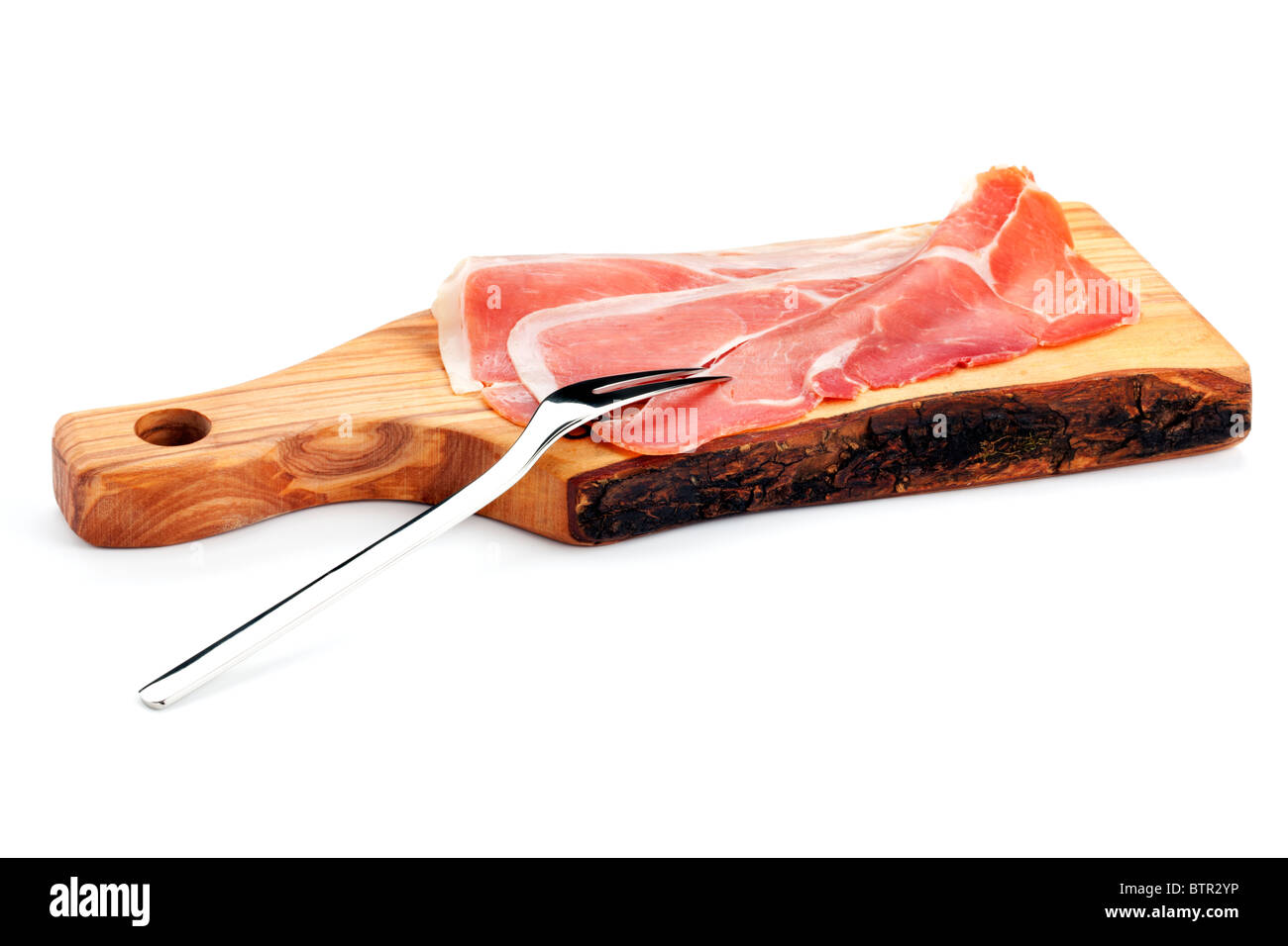 Tre fette di spagnolo dry-cured prosciutto Serrano su un tagliere di legno con una forcella di carne Foto Stock