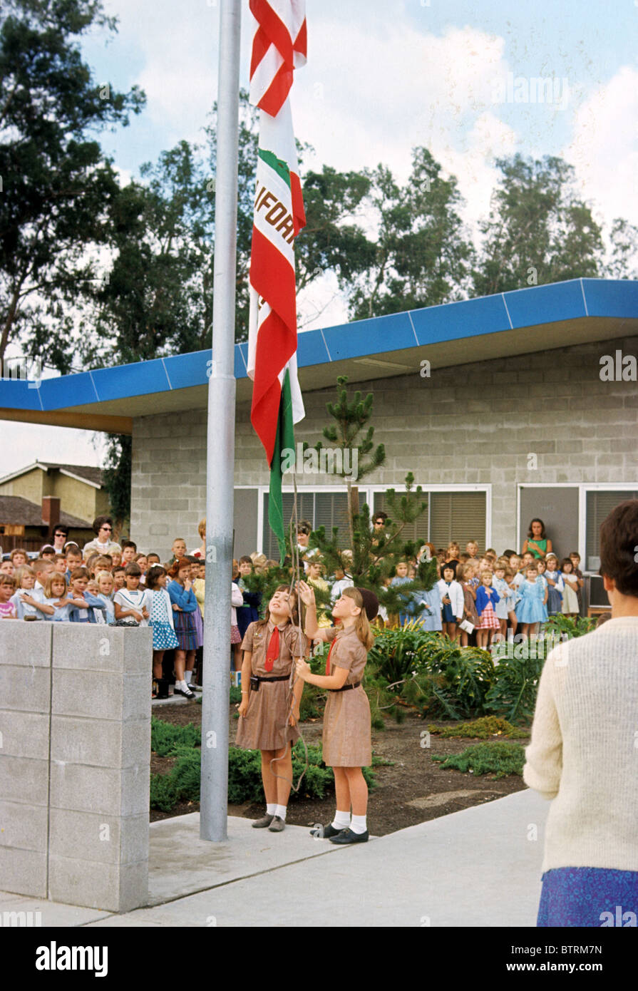 Brownie girl scout alzare bandiera polo scuola studente patriot paese nazione America USA salutare pegno allegiance onore rispetto Foto Stock