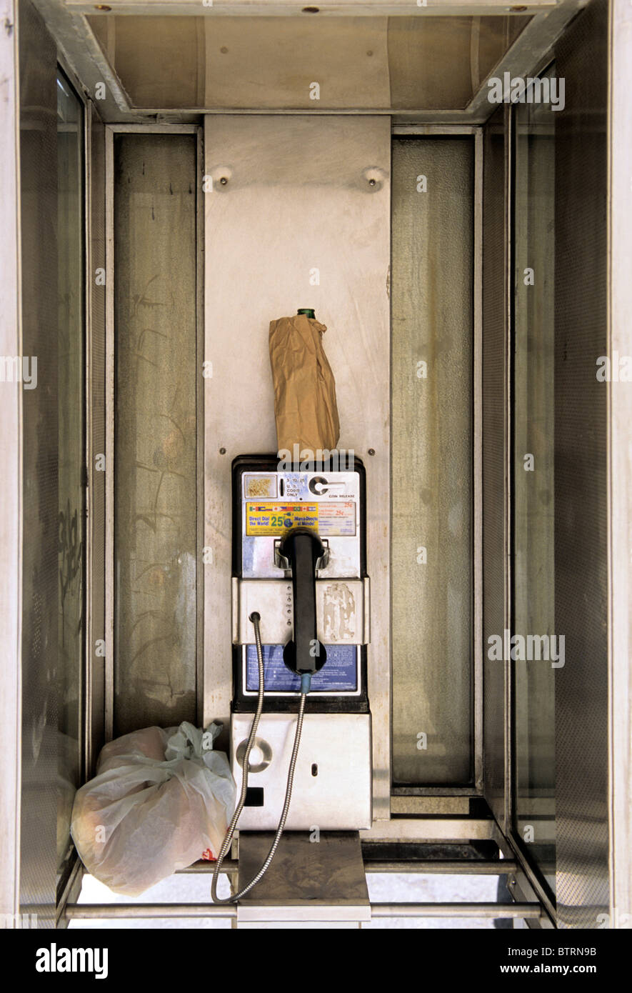 Rifiuti o rifiuti nel telefono pubblico a pagamento. telefono (cabina telefonica pubblica) (telefono) sulla strada. Sacchetto di carta marrone e sacchetto di plastica con immondizia. STATI UNITI Foto Stock