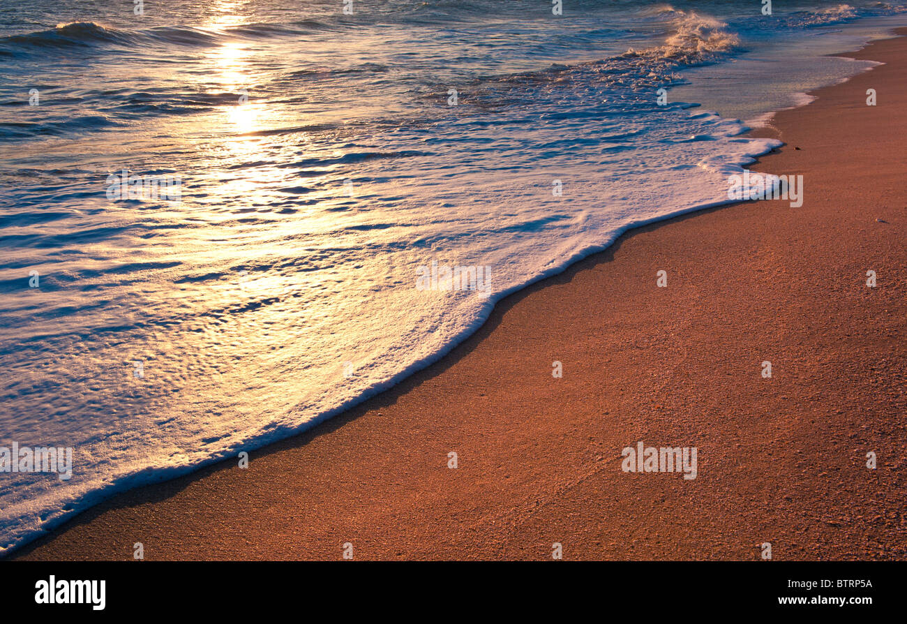 Spiaggia tranquilla sunrise. Le onde del mare, schiuma e sabbia dorata. Copyspace sfondo. Foto Stock
