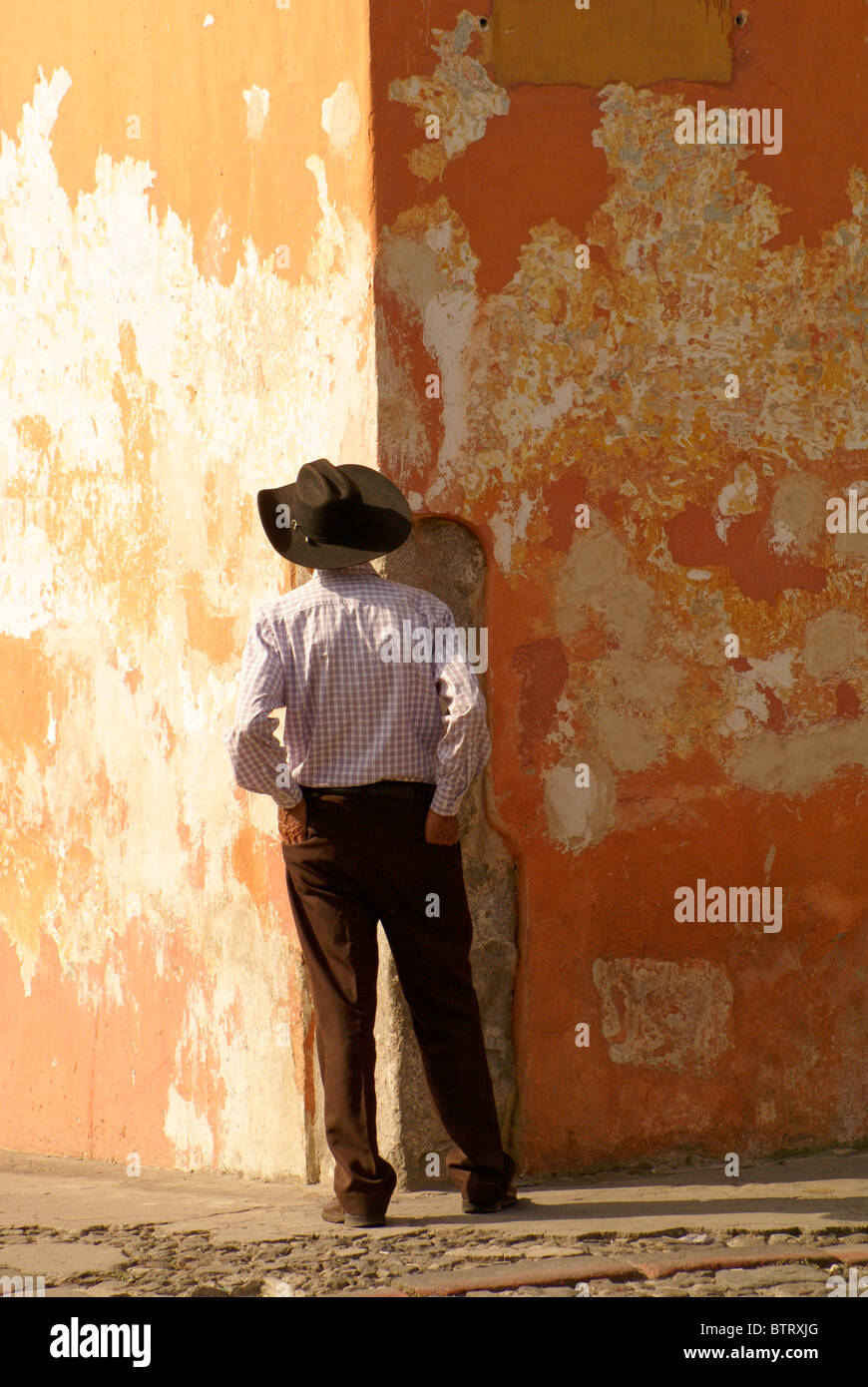 Uomo in piedi di fronte ad una parete colorata in Antigua, Guatemala. Antigua è un sito patrimonio mondiale dell'UNESCO. Foto Stock