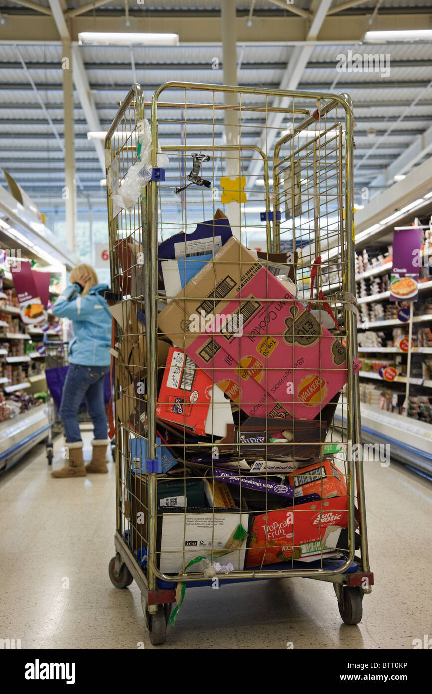 Carrello pieno di scatole di cartone di scarto e imballaggio in un'isola del supermercato. Regno Unito, Gran Bretagna Foto Stock