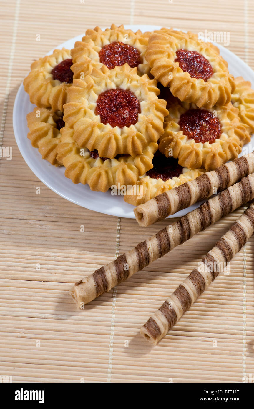 Rotoli di wafer e biscotti sul piatto bianco Foto Stock