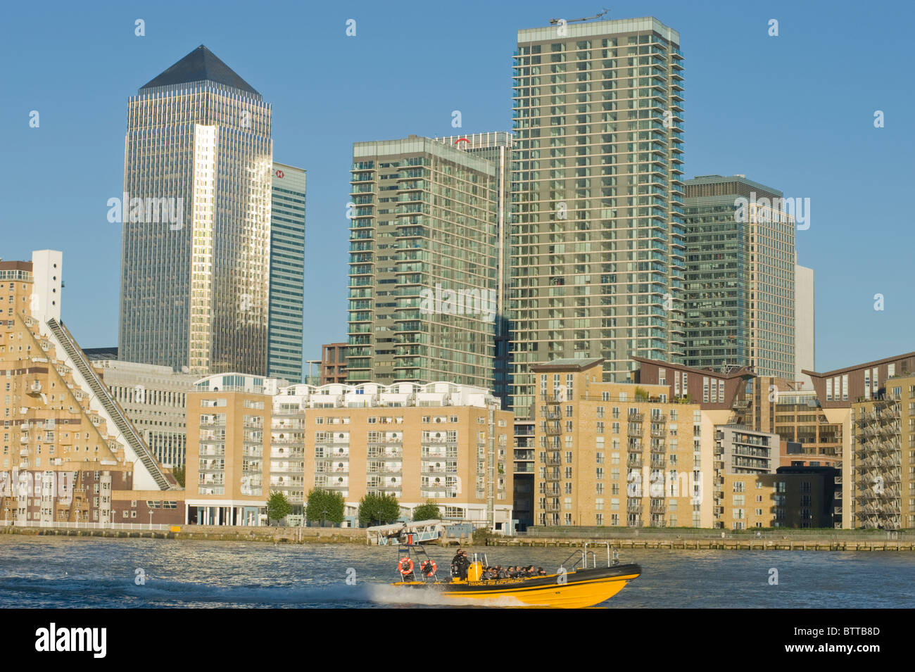 Gli edifici di Canary Wharf a Londra, con una barca dal Tamigi la nervatura esperienza passando sul Tamigi in primo piano. Foto Stock