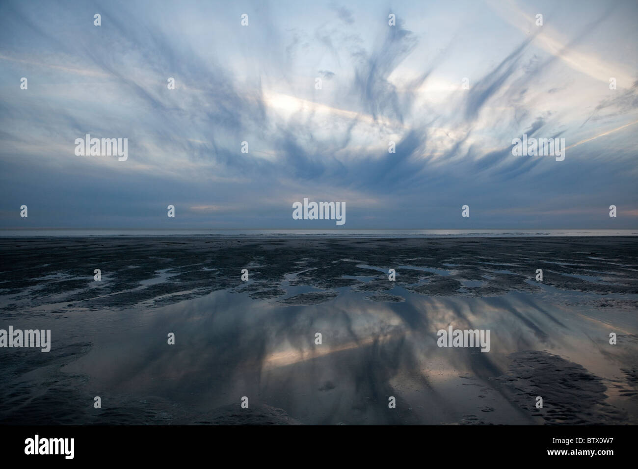 Cielo drammatico riflettendo in acqua al tramonto sulla spiaggia, a Le Touquet, Francia Foto Stock