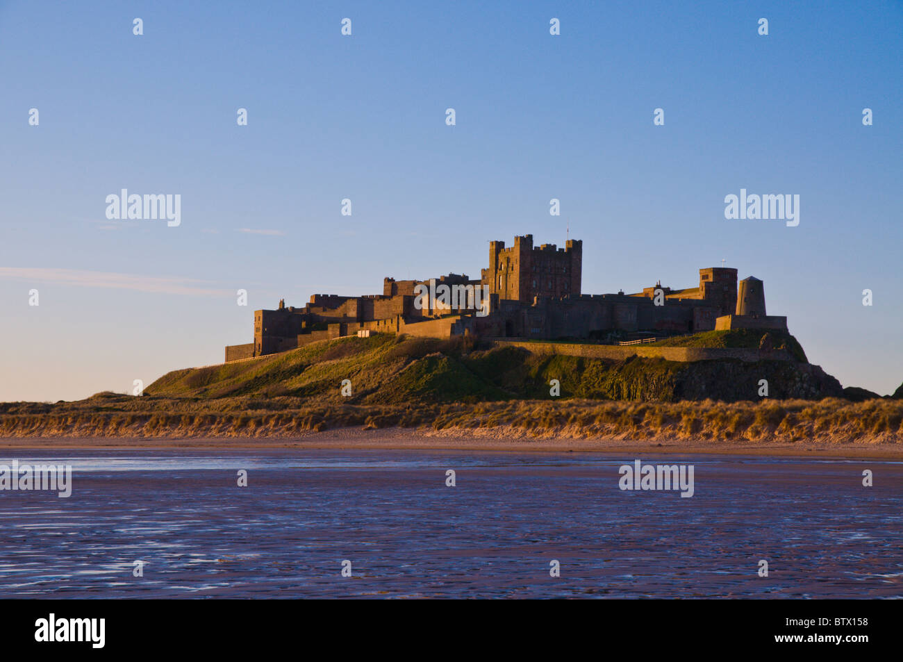 La mattina presto luce su Bamburgh castle e la spiaggia in Northumberland, Inghilterra. Foto Stock