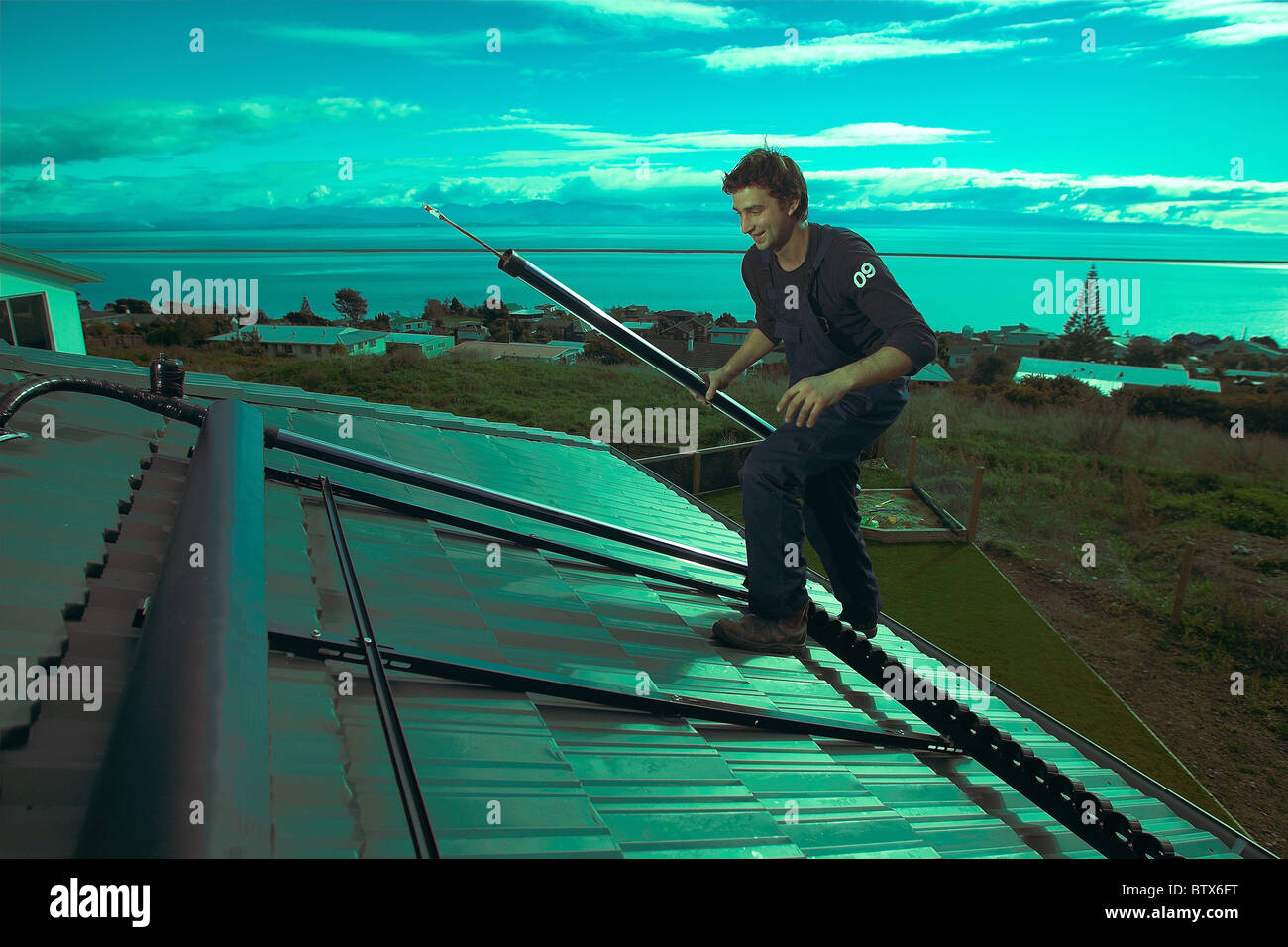 Artigiano qualificato installazione solare di acqua calda sistema a una casa, Nelson, Nuova Zelanda, la città con la più alta ore di sole. Foto Stock
