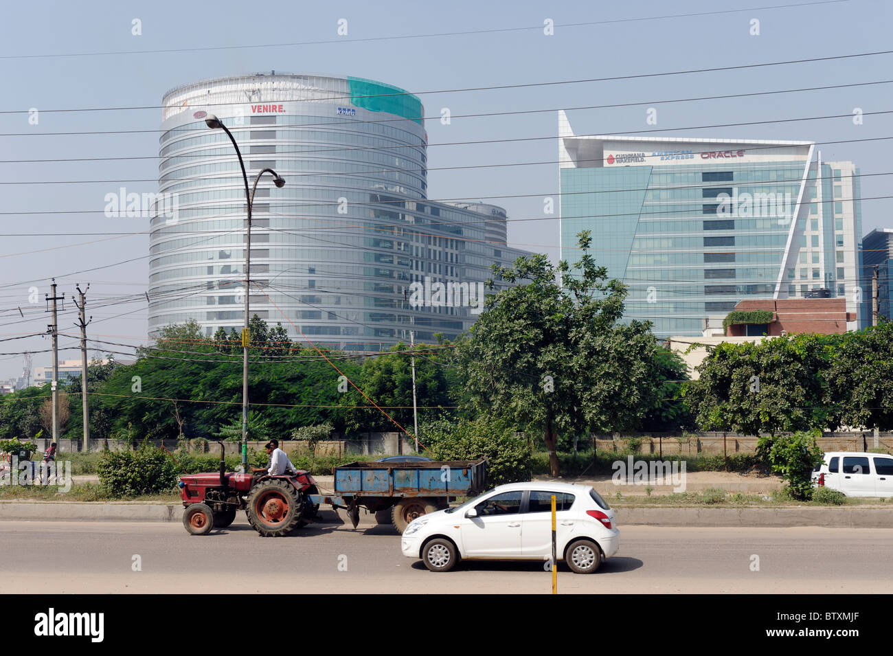 Auto moderna e vecchio trattore su strade f Gurgaon, la tecnologia di città a sud di Delhi, India Foto Stock