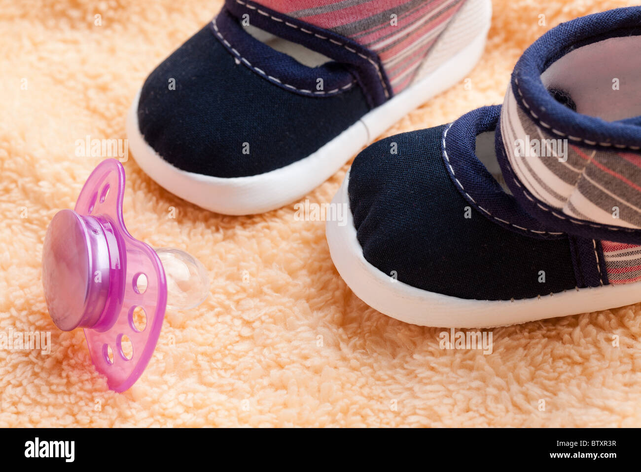Il succhietto e scarpe per bambini su uno sfondo morbido Foto Stock