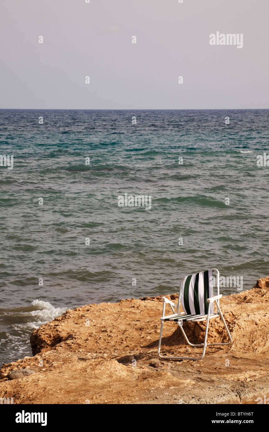 Abbandonata la sedia pieghevole sulle rocce a governatori Bay, Cipro Foto Stock