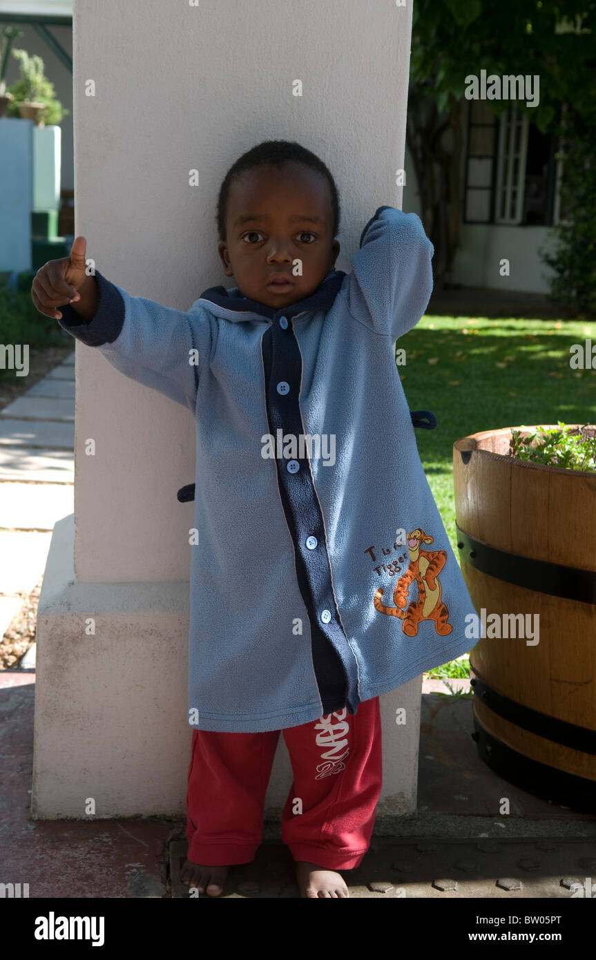 Ritratto di un bambino sudafricano che indossa pigiama e abito blu, appoggiato su una colonna di pietra, Sudafrica Foto Stock