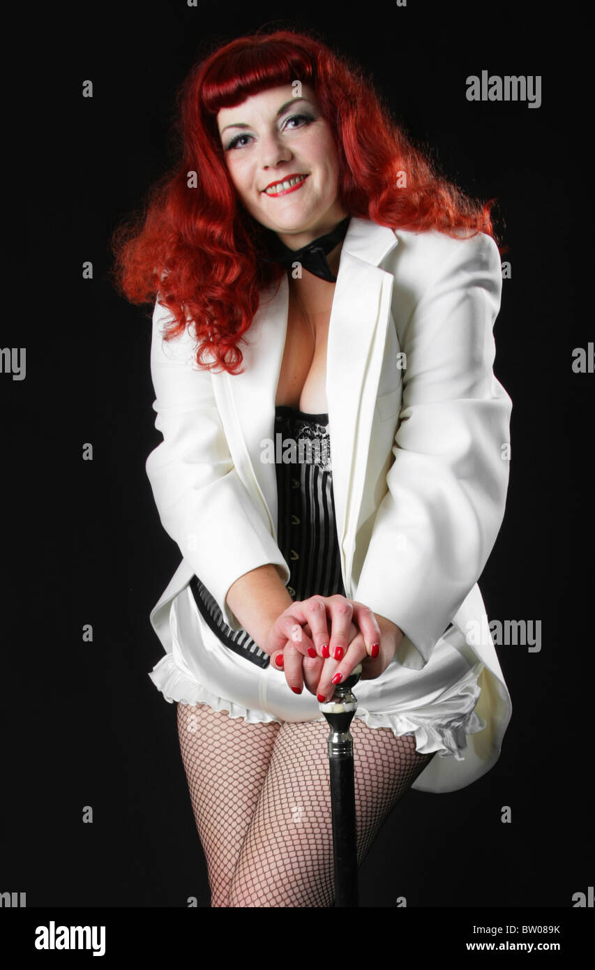 Rosso giovane intitolata Burlesque Performer che indossa un mantello bianco, Bow tie-in e basco e tenendo una canna. Foto Stock