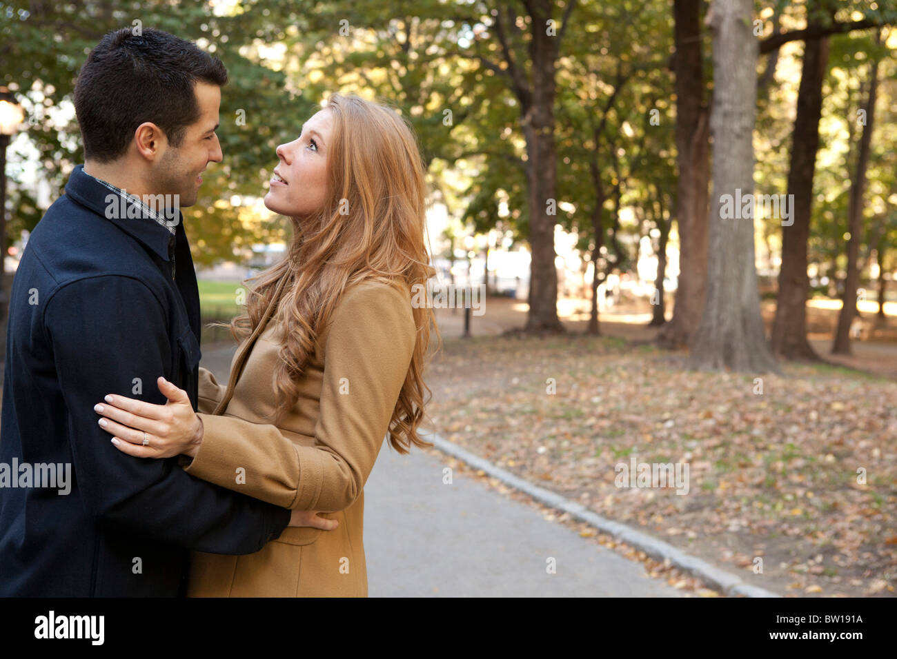 Una giovane coppia abbraccio nel Central Park di New York. Lei si guarda verso il cielo. Foto Stock