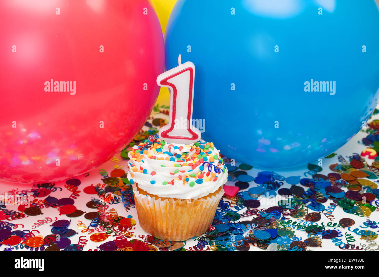 Celebrazione con palloncini, coriandoli, tortina, e numero 1 candela. Foto Stock