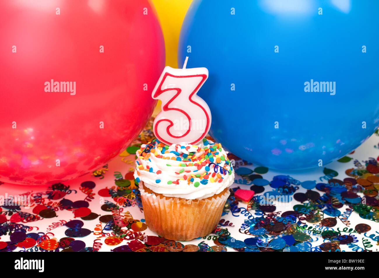 Celebrazione con palloncini, coriandoli, tortina, e numero 3 candela. Foto Stock