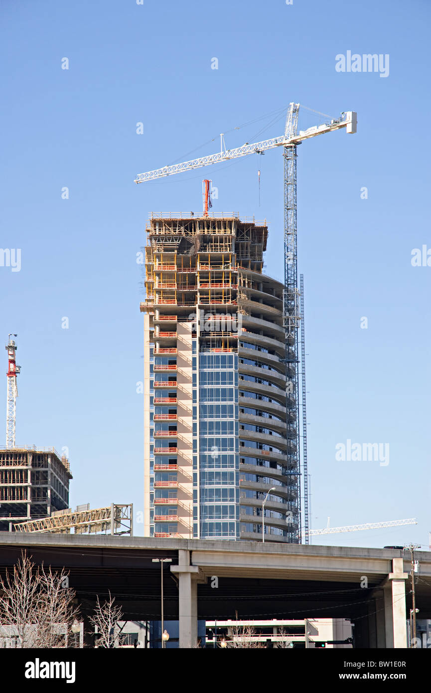 Un alto edificio di uffici in fase di costruzione con una enorme gru. Foto Stock
