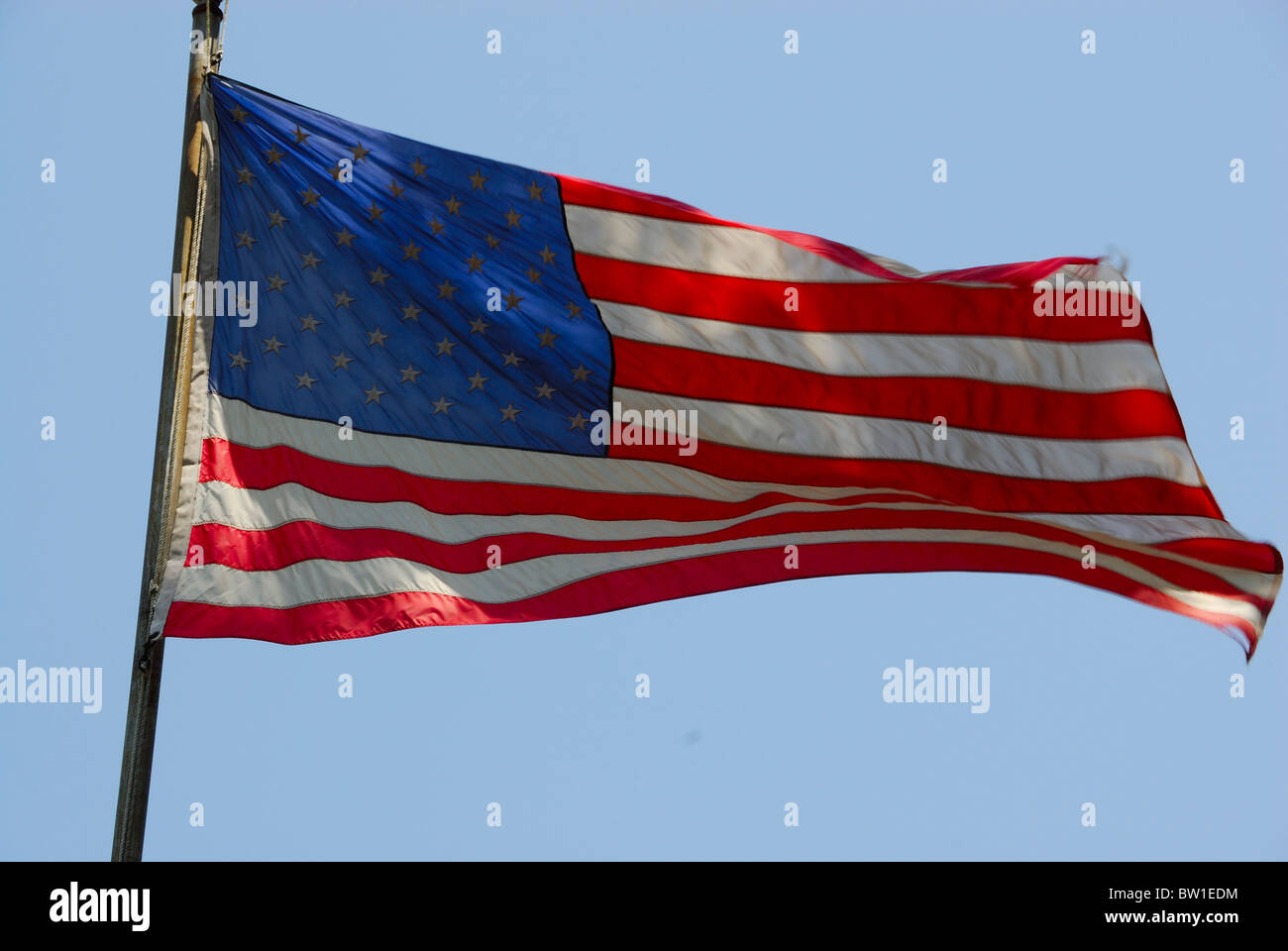 Bandiera degli Stati Uniti d'America volare libero nel vento contro un luminoso cielo blu. Foto Stock