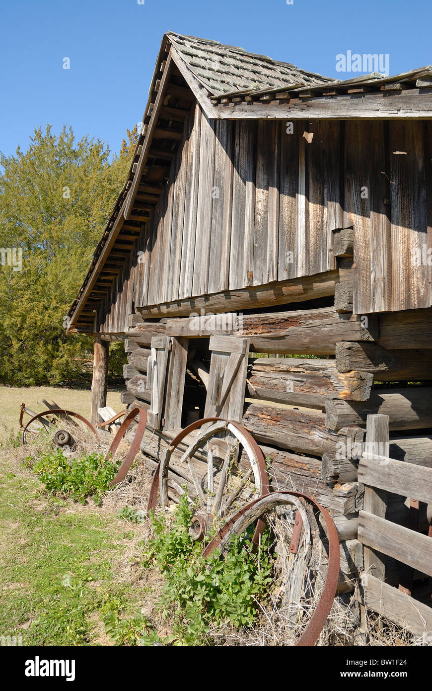 In legno antico fienile di registro con il vecchio carro in legno ruote che poggiano contro un lato. Foto Stock
