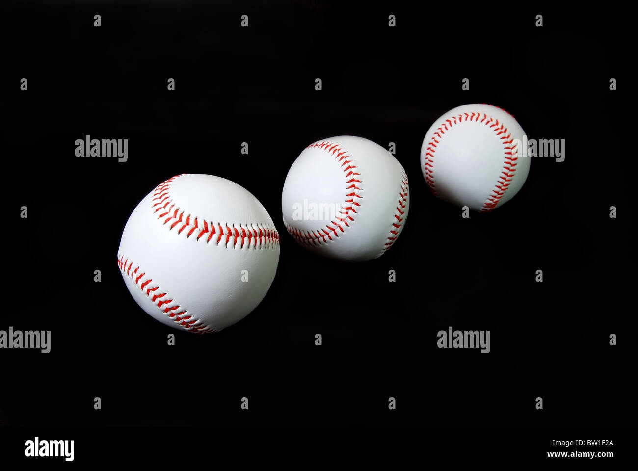 Tre baseballs isolati su sfondo nero. Foto Stock