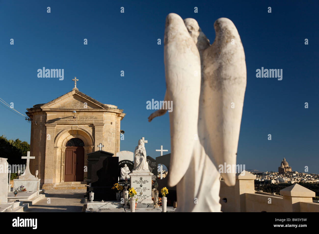 Trattenuta cappelle di pietra in contrasto con il barocco ornato di lapidi per ornare tombe nei cimiteri delle isole maltesi. Foto Stock