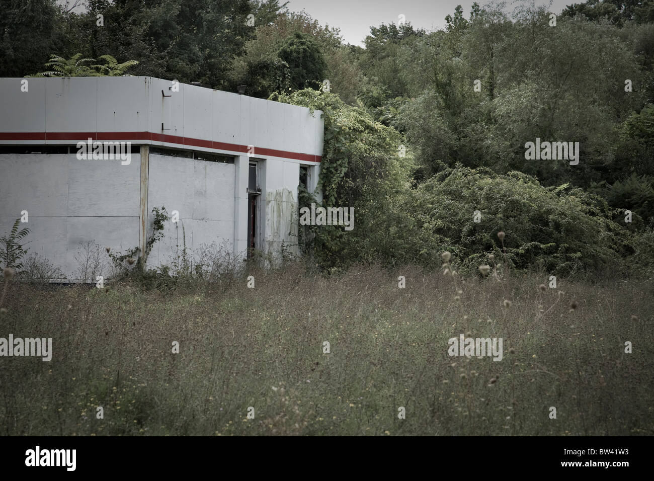 Un vecchio malandato e abbandonata la stazione di gas nel campo incolto Foto Stock