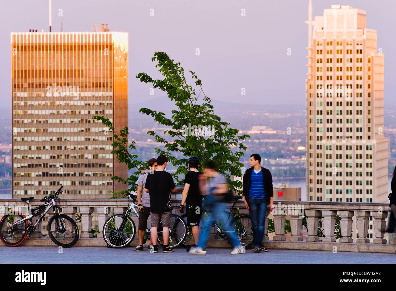 Giovani uomini appeso attorno al Belvedere e gli edifici al tramonto, Montreal, Quebec Foto Stock