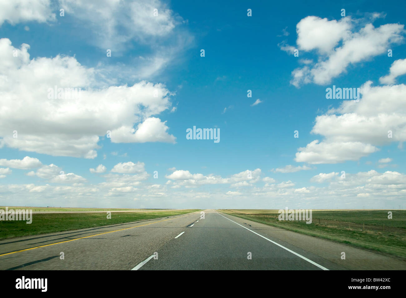 Autostrada circondata da innumerevoli campi e Big Blue Skies, Alberta, Canada Foto Stock