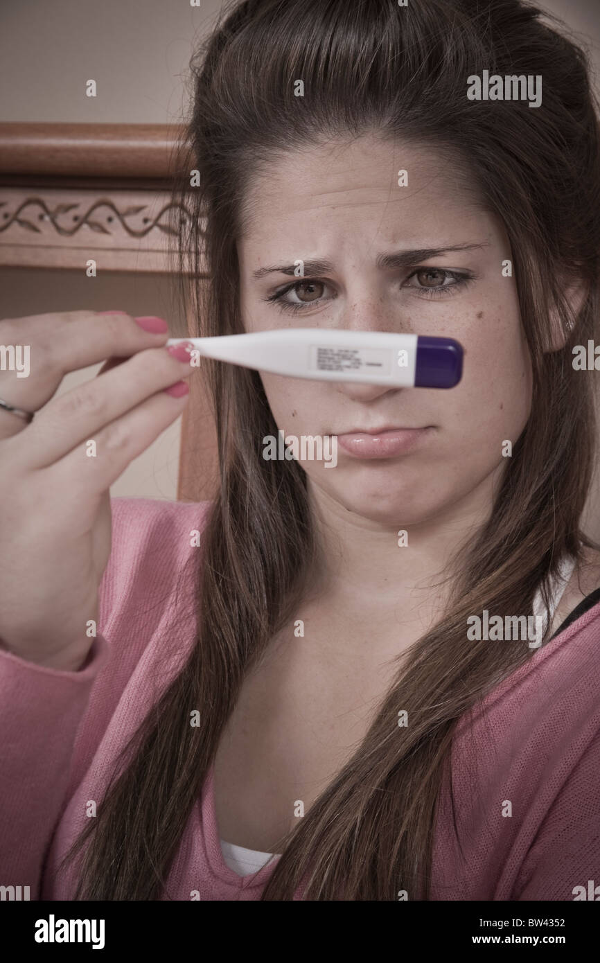 Teen ragazza (15 anni di età) guardando un termometro Foto Stock