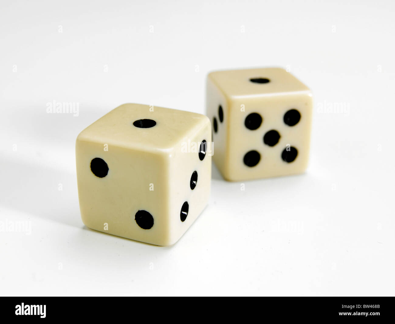 Una coppia di selettivamente concentrati white dice che mostra uno alla parte superiore su sfondo bianco Foto Stock