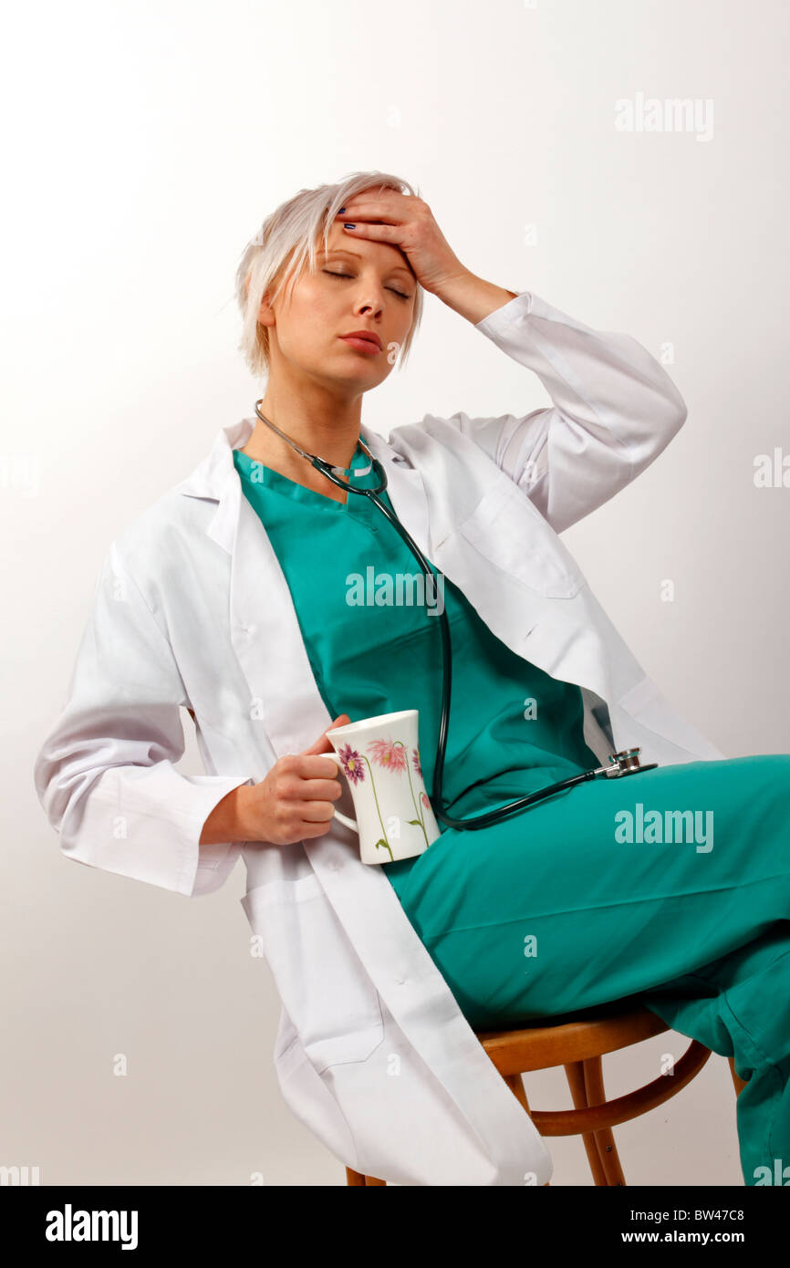 Giovane medico dopo un lungo turno di lavoro cercando esaurito a bere caffè Foto Stock