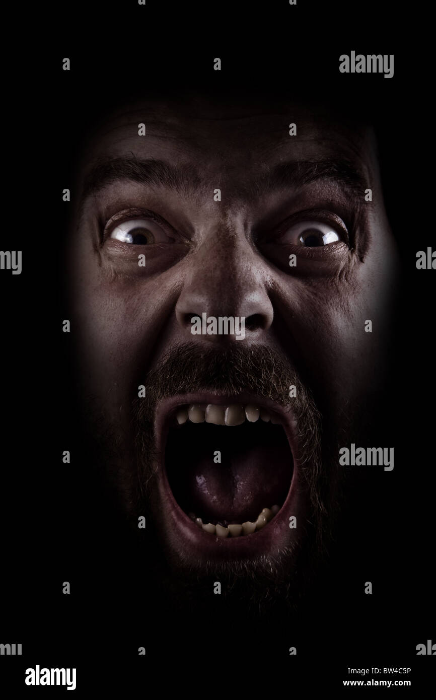 Spaventata volto di spooky uomo nel buio Foto Stock
