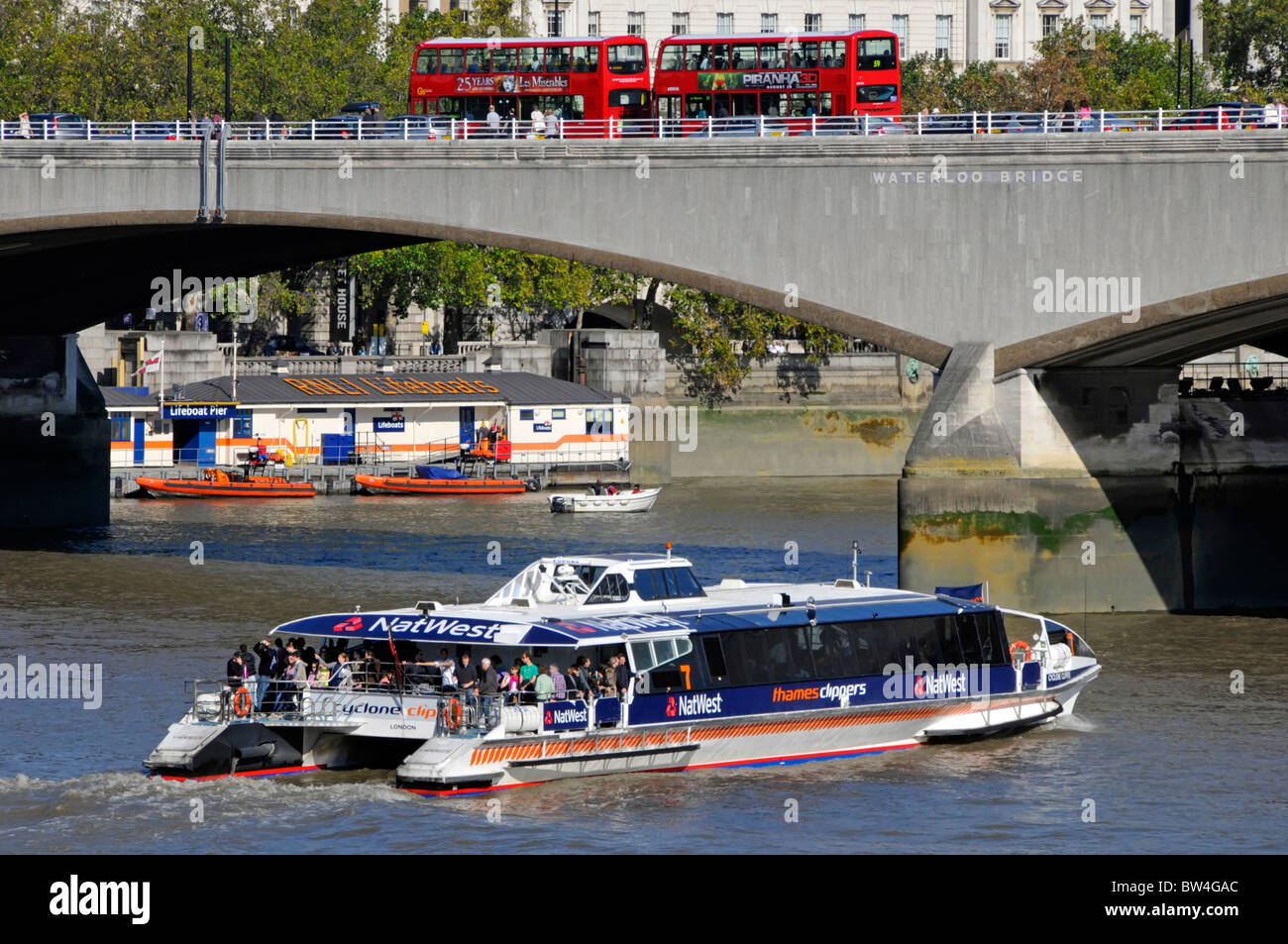 Waterloo Bridge (noto anche come Ladies Bridge) con RNLI Lifeboat Station e pubblicità NatWest Bank sull'autobus fluviale Thames Clipper Londra Inghilterra Regno Unito Foto Stock