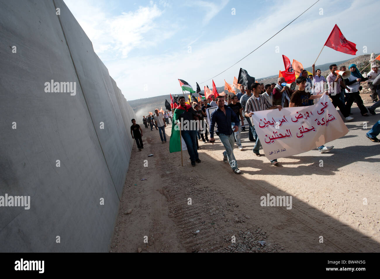 Palestinesi marzo in una protesta non violenta contro il popolo israeliano barriera di separazione in Cisgiordania città di Al-Walaja. Foto Stock