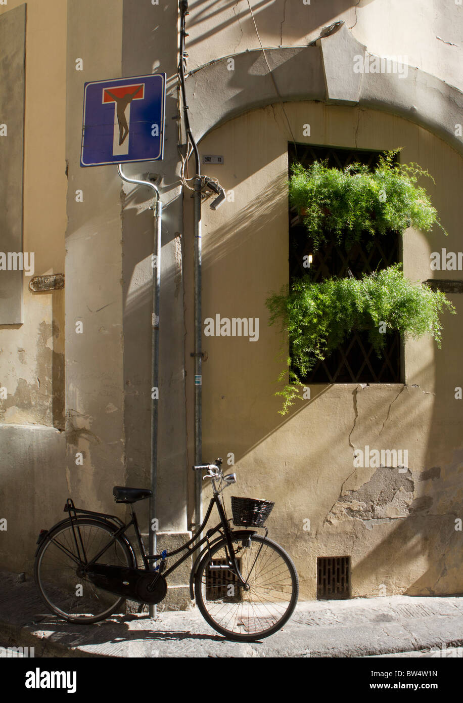 Una bicicletta parcheggiata su un angolo di strada al di sotto di un 'no attraverso la strada' segno deturpata da artista Clet Abraham con una figura di Cristo Foto Stock