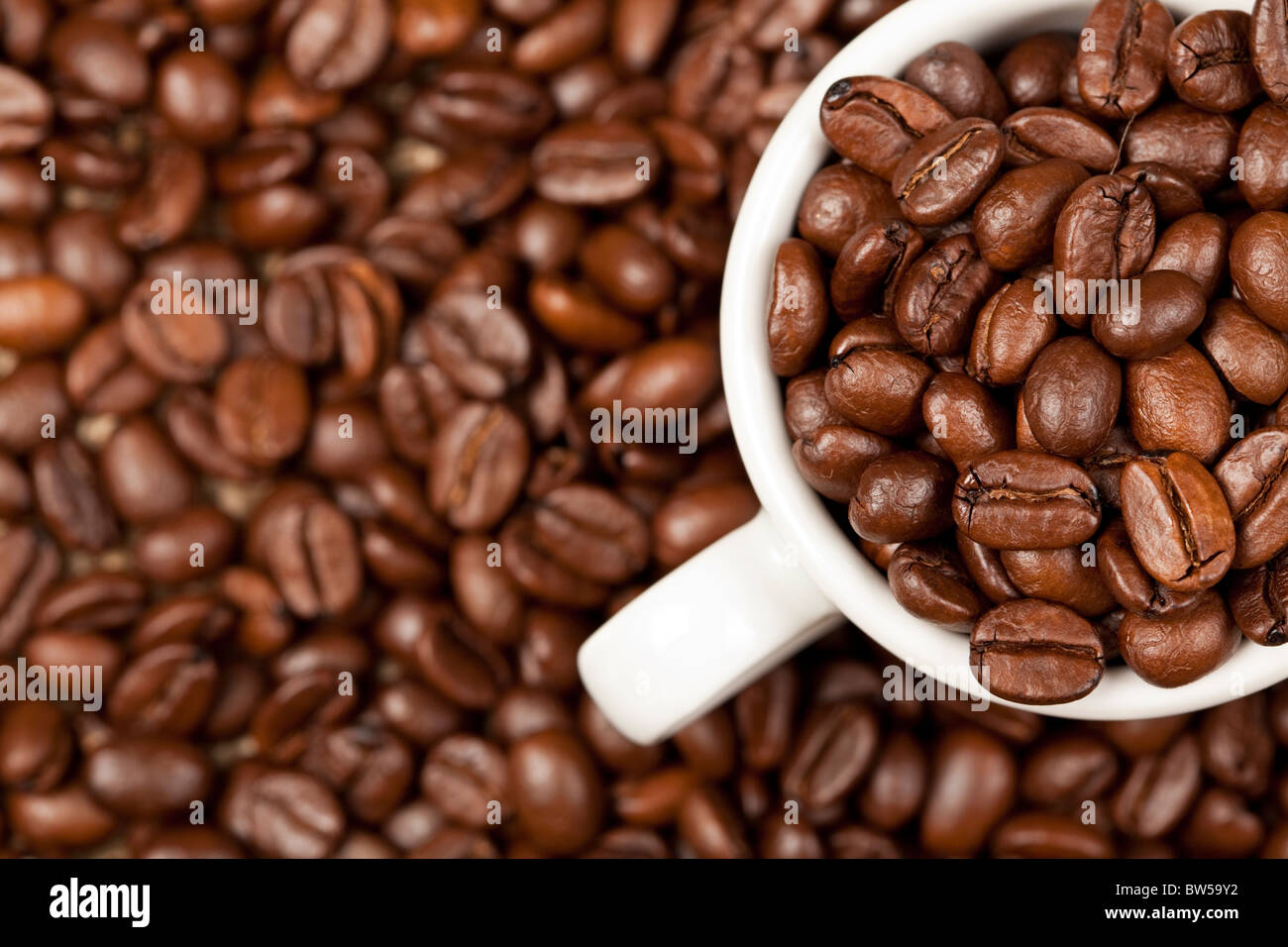 Tazzina piena di caffè torrefatto in grani. In fondo sono ulteriormente chicchi di caffè visibile. Foto Stock