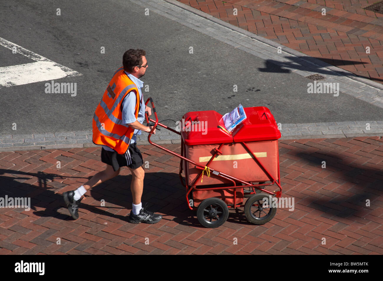 Il postino ha spinto in fretta il suo carrello di posta attraverso la strada a Poole, Dorset UK in agosto Foto Stock